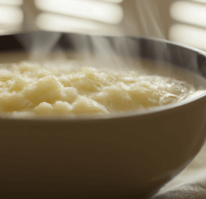 Can Dogs Eat Grits? Bowl of cooked grits on a wood table with steam rising from the surface